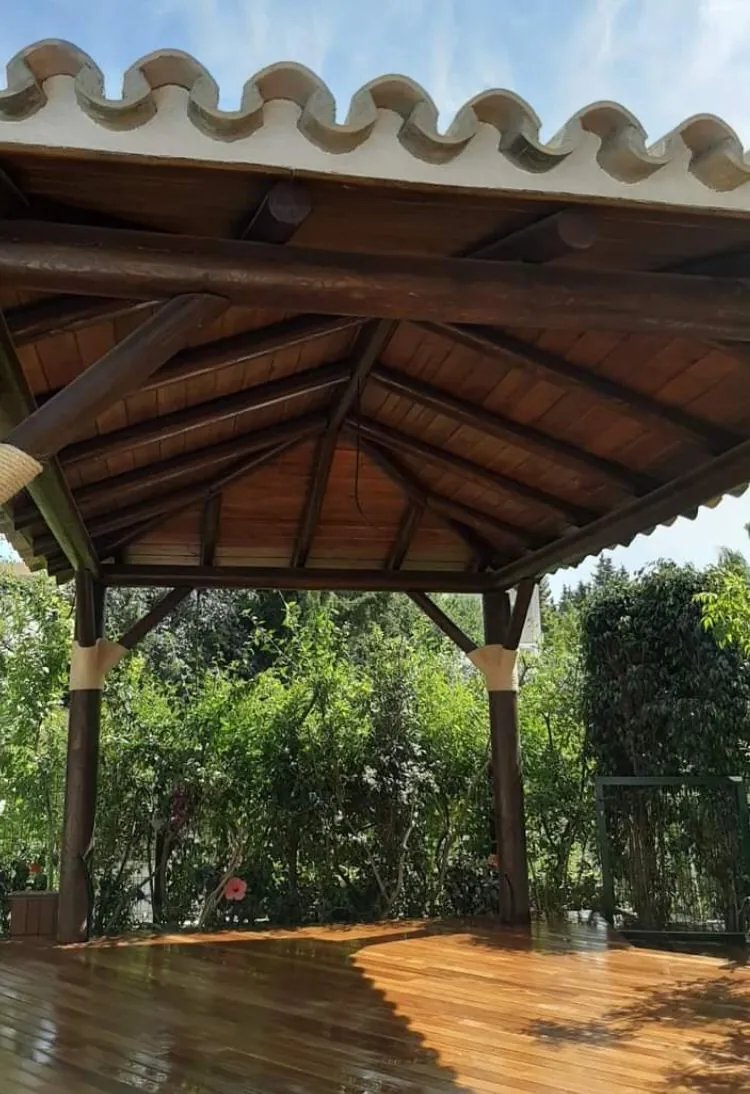 Cenador octogonal de madera con cubierta de paja en jardín de Marbella